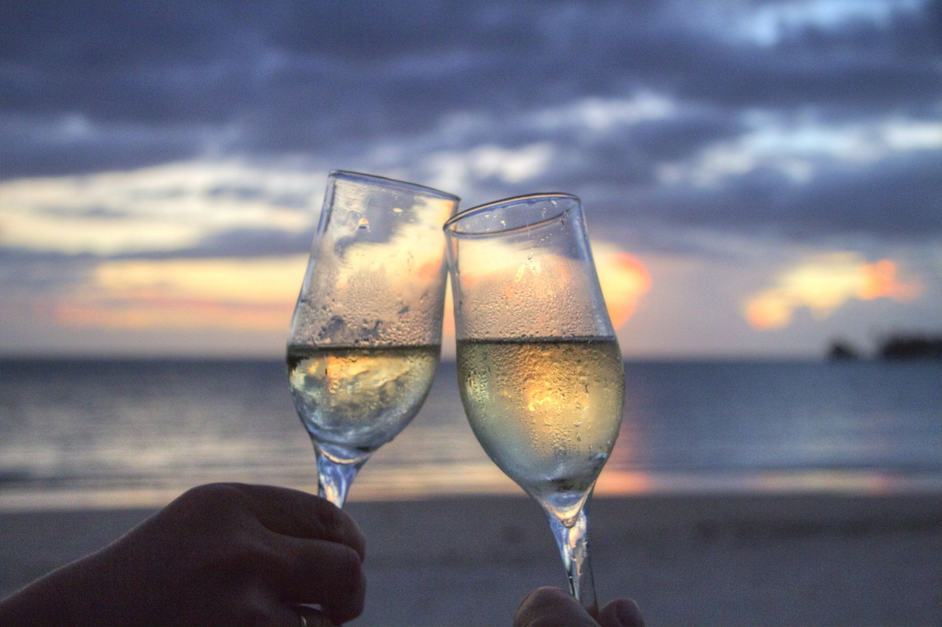 Chilled champagne glasses toast at luxury resort oceanfront terrace at sunset