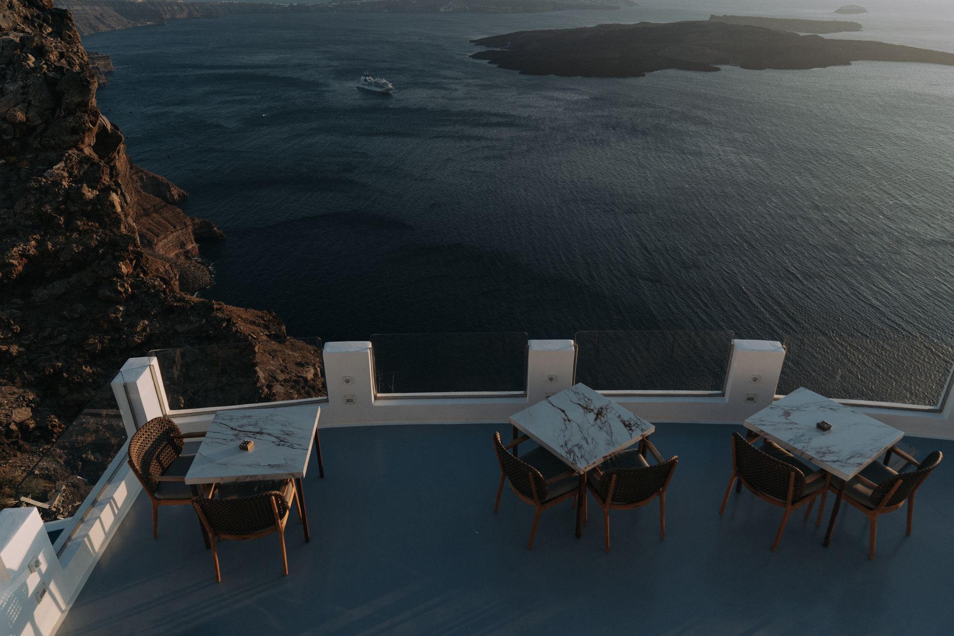 Affluent couple enjoying private sunset dinner on seaside terrace booked through high-touch travel advisor