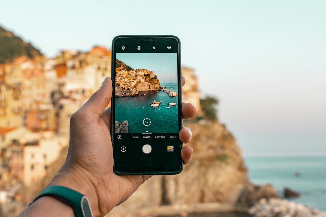 Travel creator recording 4K vertical video with smartphone on scenic mountain overlooking Mediterranean